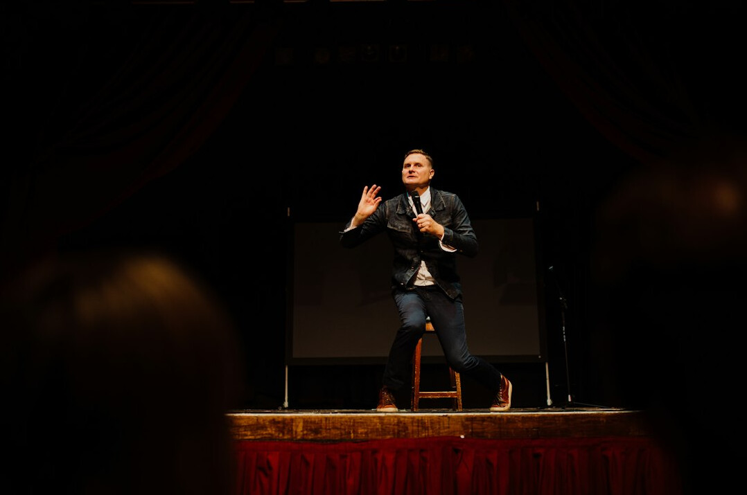 Confident speaker presenting on stage to a seated audience